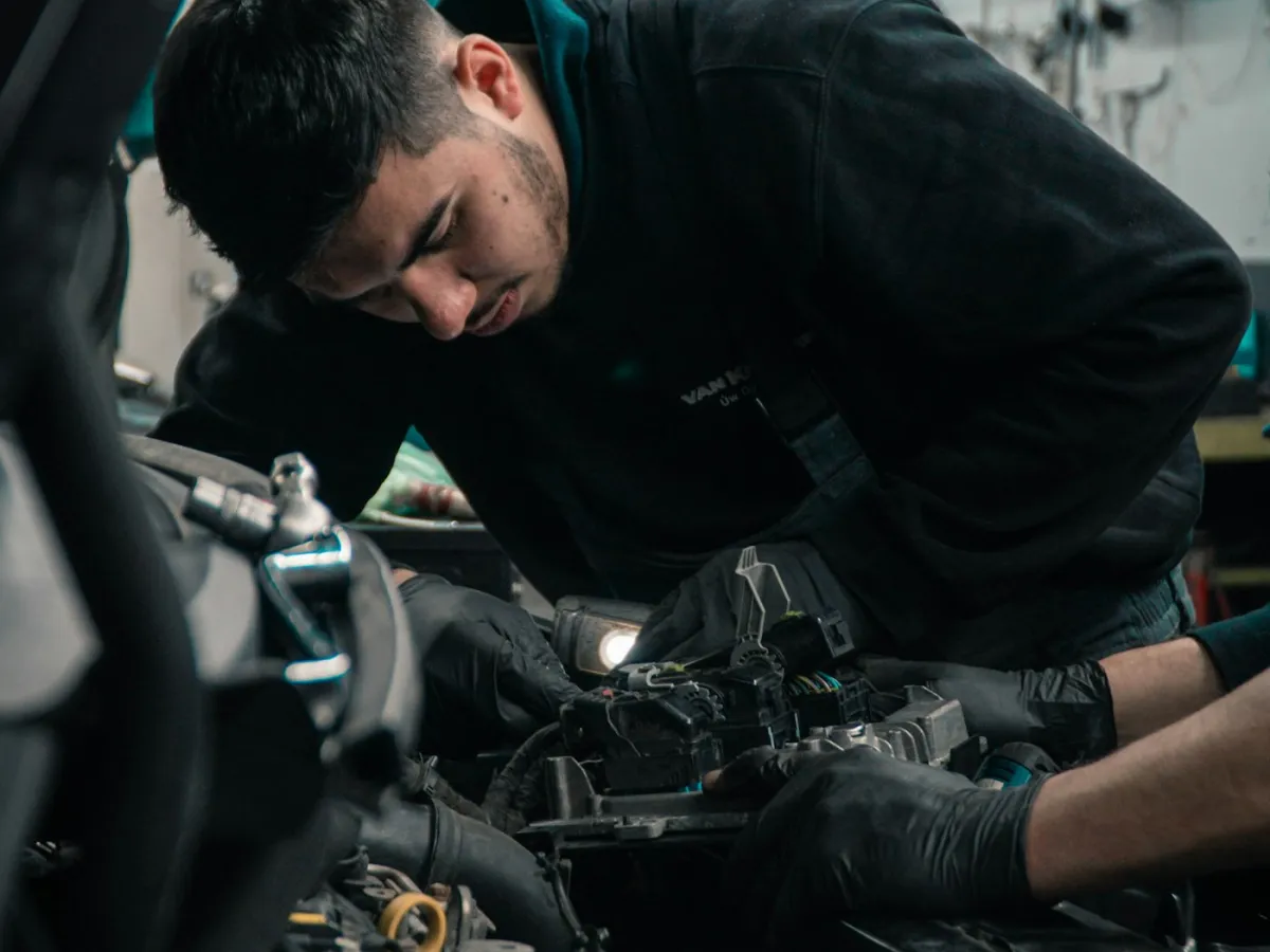 Mechanic working under the bonnet of a car in a workshop